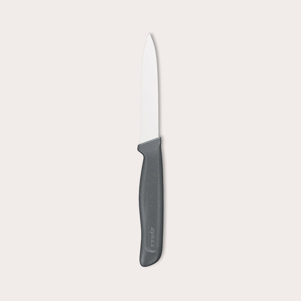 The Zyliss Paring Knife Serrated 10cm / 4, featuring a black ergonomic handle and eco-friendly material, is displayed against a plain white background. 