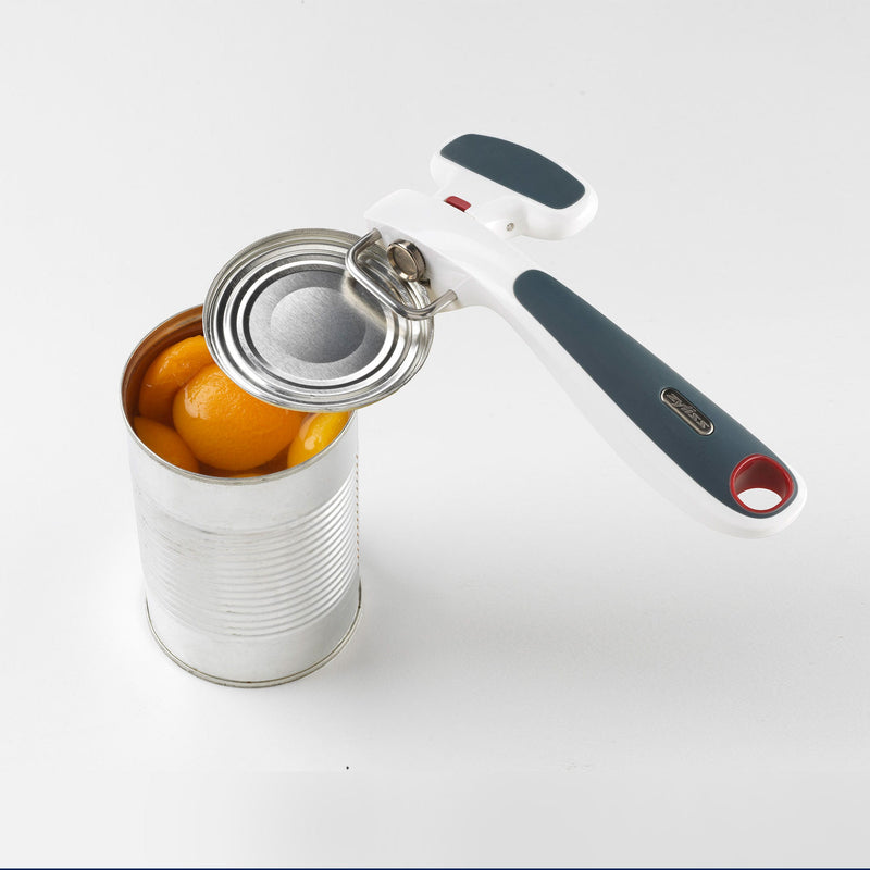 A can of peaches in syrup is opened with the Zyliss Safe Edge Can Opener, which has an ergonomic design and rests atop the can against a white background. 