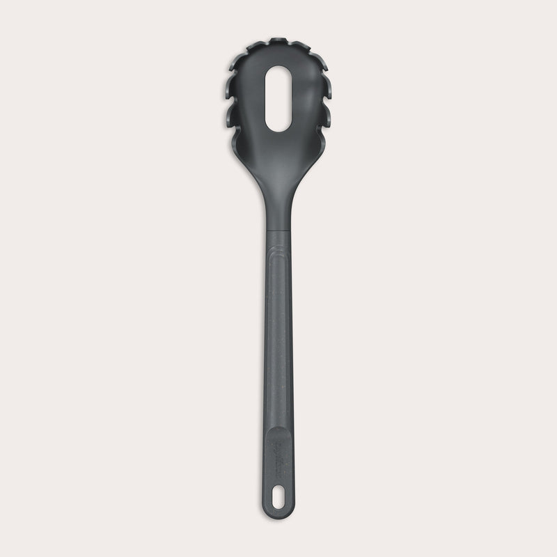 The Zyliss Spaghetti Server is a black, heat-resistant utensil with a long handle and slotted, rounded head featuring prongs for ideal portion control, shown isolated on a light background. 