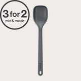 A dark gray Zyliss Spoon with a long handle, heat-resistant and dishwasher safe, stands vertically on a light background. A circular 3 for 2 mix & match offer label appears in the top left corner.#Medium